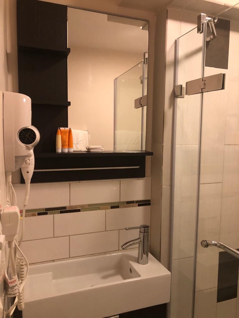 A modern bathroom with a white sink, a mirror above it, and a glass shower enclosure.