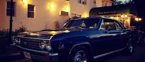 A classic black car parked in front of a building with a sign reading "James Hook Hotel".