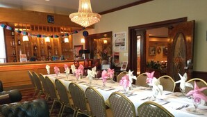 A formal dining room with a long table set for a meal, surrounded by upholstered chairs. - Jones Beach Hotel (Wantagh)
