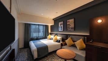Habitación de hotel con cama, mesitas de noche, escritorio, silla, televisor y ventana con cortinas.