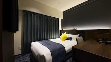 A hotel room with a bed, a desk, a chair, and a television.