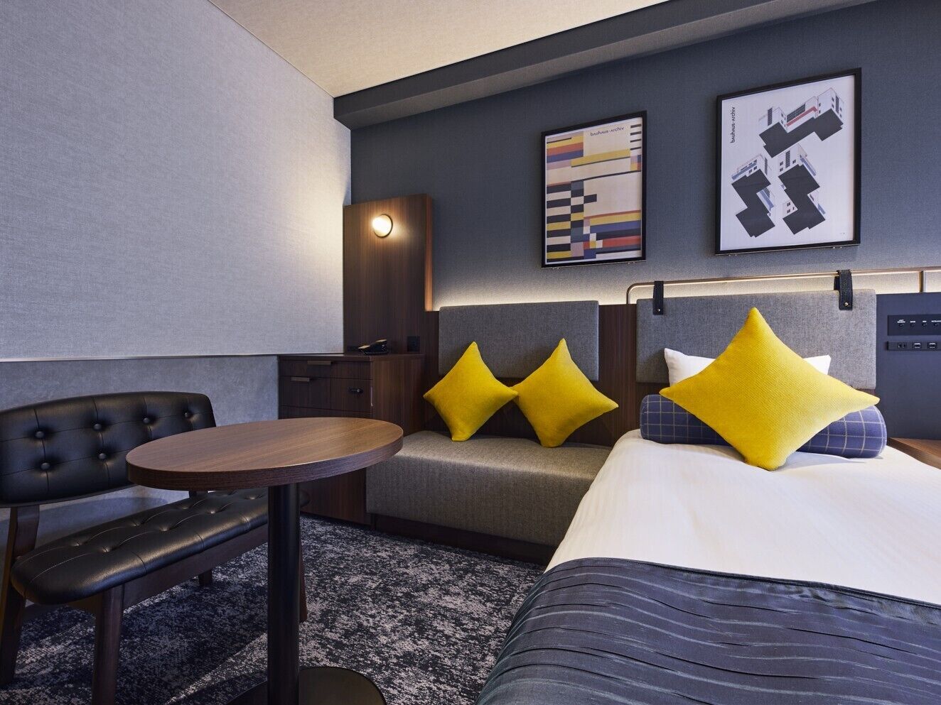 Habitación de hotel con cama, una mesita redonda, un sofá y televisión de pared.