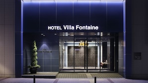 La entrada al HOTEL Villa Fontaine, con un diseño moderno, presenta una puerta de vidrio y una planta en maceta.