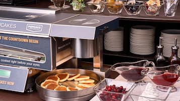 A commercial kitchen with a coffee machine, a plate rack, and various food items like pancakes and berries.