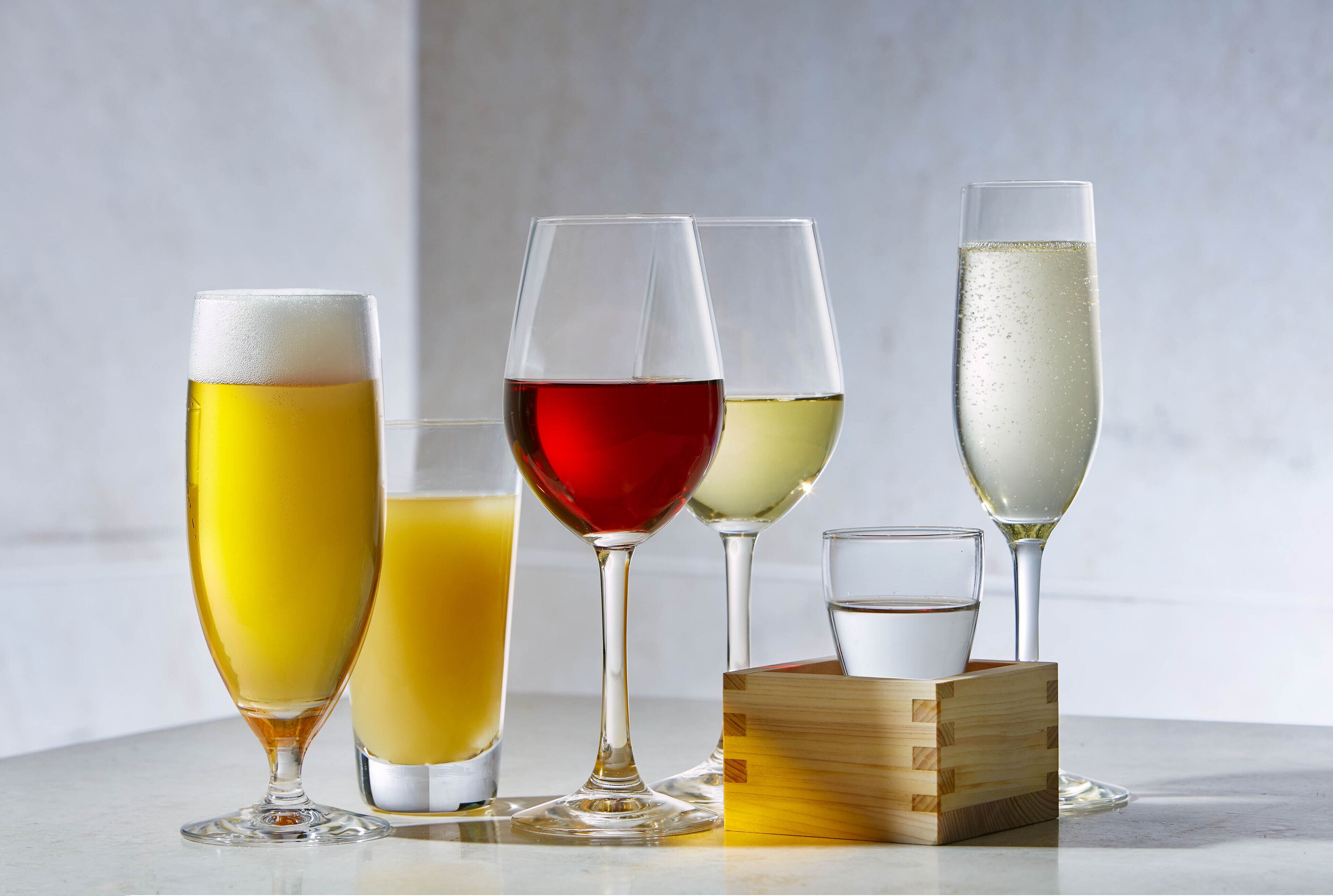 Cinq verres contenant différentes boissons, posés sur une surface en marbre.
