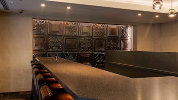 Uma área de bar com um balcão comprido, banquetas e painéis decorativos na parede.
