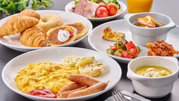 A breakfast spread with croissants, eggs, sausages, and various dishes.