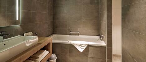 Un baño moderno con una bañera grande, un lavabo y un mueble de tocador de madera.
