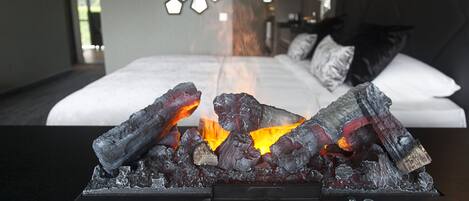 Una habitación de hotel moderna con cama, un adornado muro y una chimenea con leña.