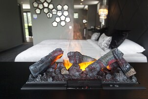 Una habitación de hotel moderna con cama, un adornado muro y una chimenea con leña.