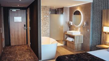 A modern hotel bathroom with a bathtub, a sink, and a mirror.