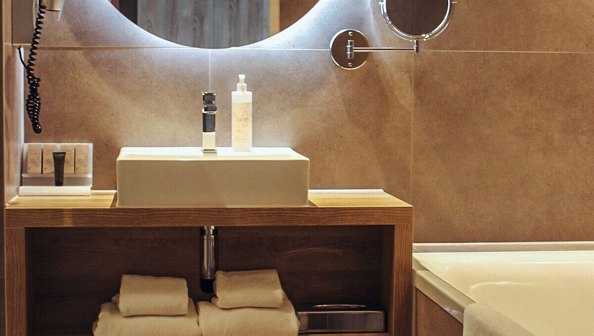A bathroom with a wooden vanity, a sink, a mirror, a towel rack, and a bathtub.