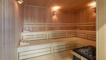 Una sauna con bancos de madera y un cubo de basura negro.