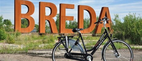 Una bicicleta estacionada frente a un gran letrero con la palabra "BREDA".