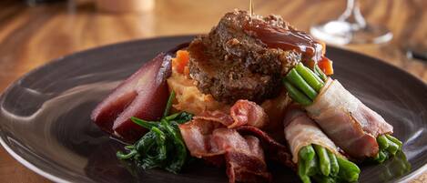 A plate of food with steak, green beans, and bacon.