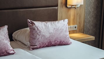 A bed with two pillows, a bedside table, and a wall-mounted light fixture.