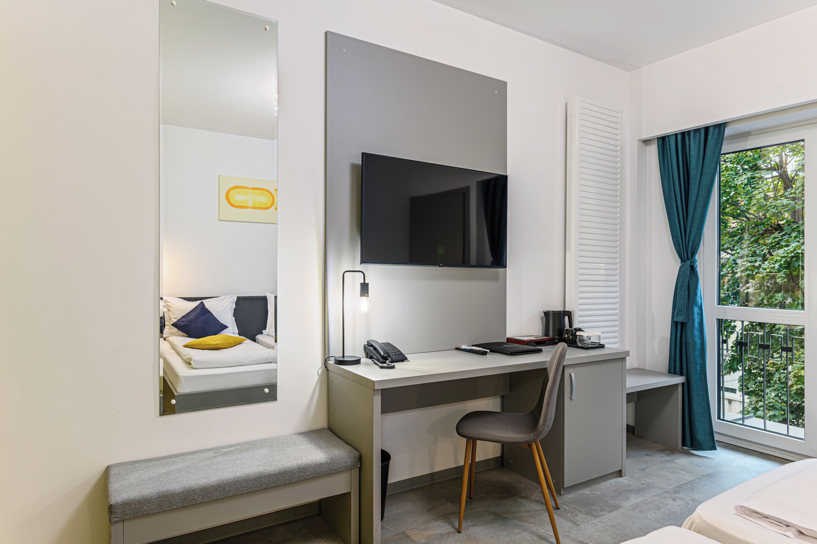 A hotel room with a desk, chair, and a bed.