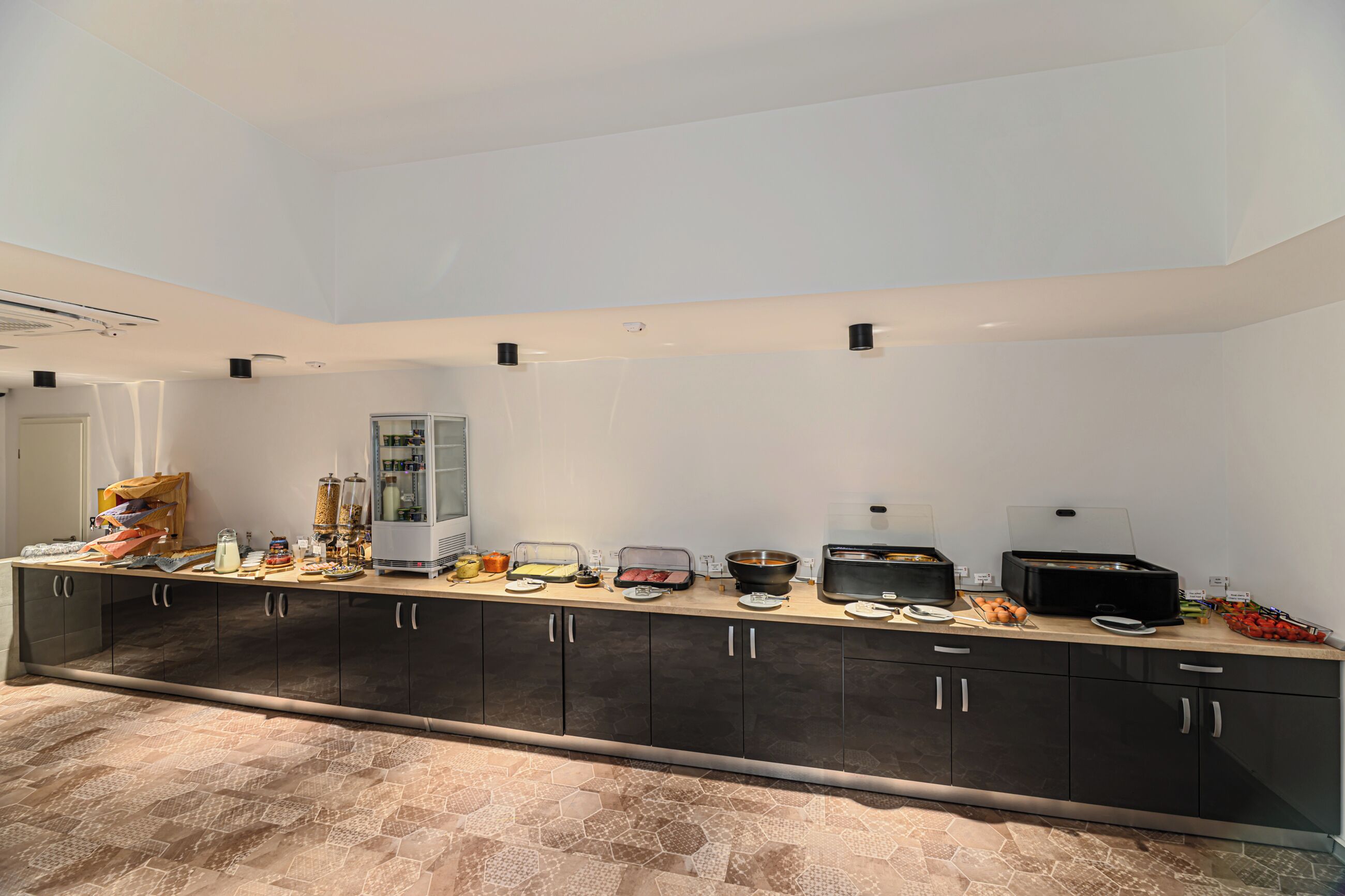 Una cocina moderna con una encimera larga, equipada con diversos electrodomésticos y alimentos.