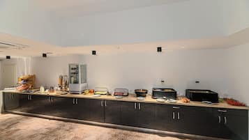 Una cocina moderna con una encimera larga, equipada con diversos electrodomésticos y alimentos.