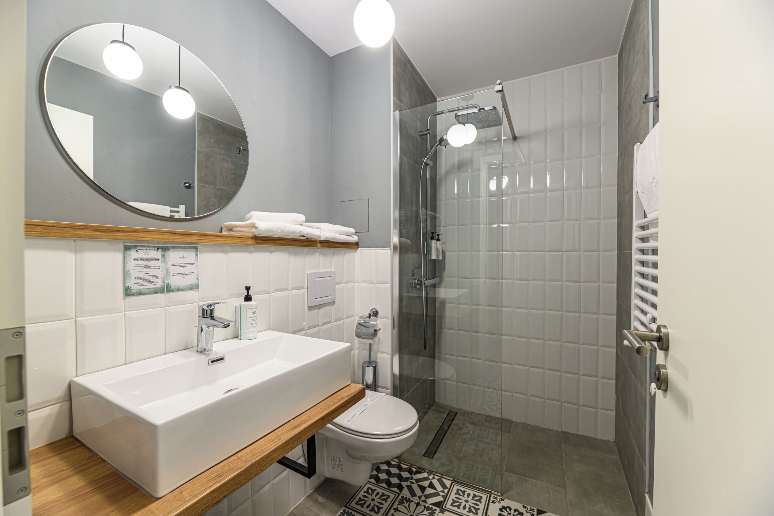A modern bathroom with a white sink, mirror, and shower.
