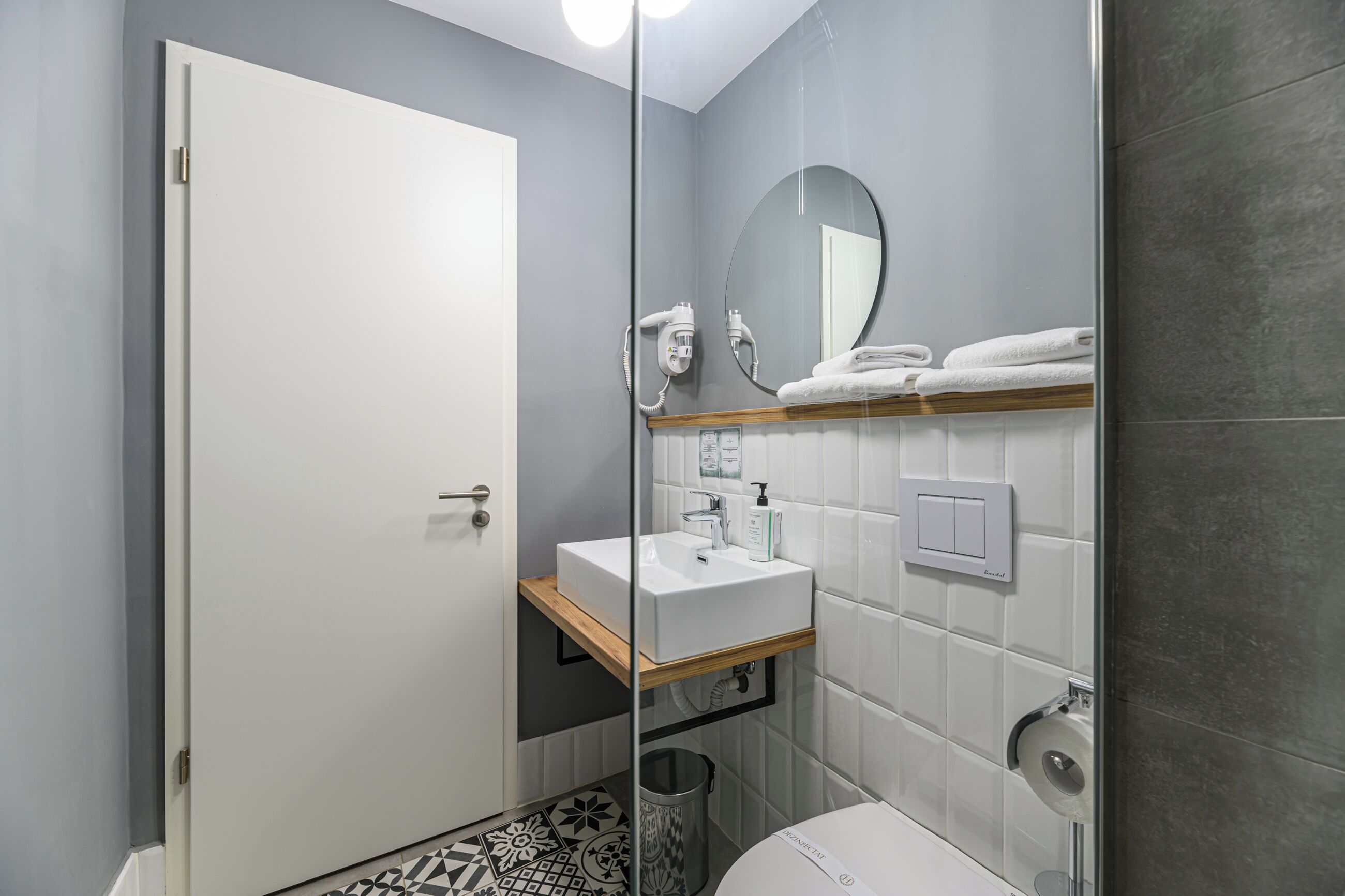A modern bathroom with a white sink, a mirror, and a toilet.