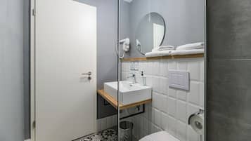 A modern bathroom with a white sink, a mirror, and a toilet.