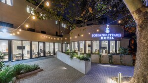 The Johann Strauss Hotel with a courtyard featuring outdoor seating, a brick pathway, and string lights. - Johann Strauss (Bucharest)