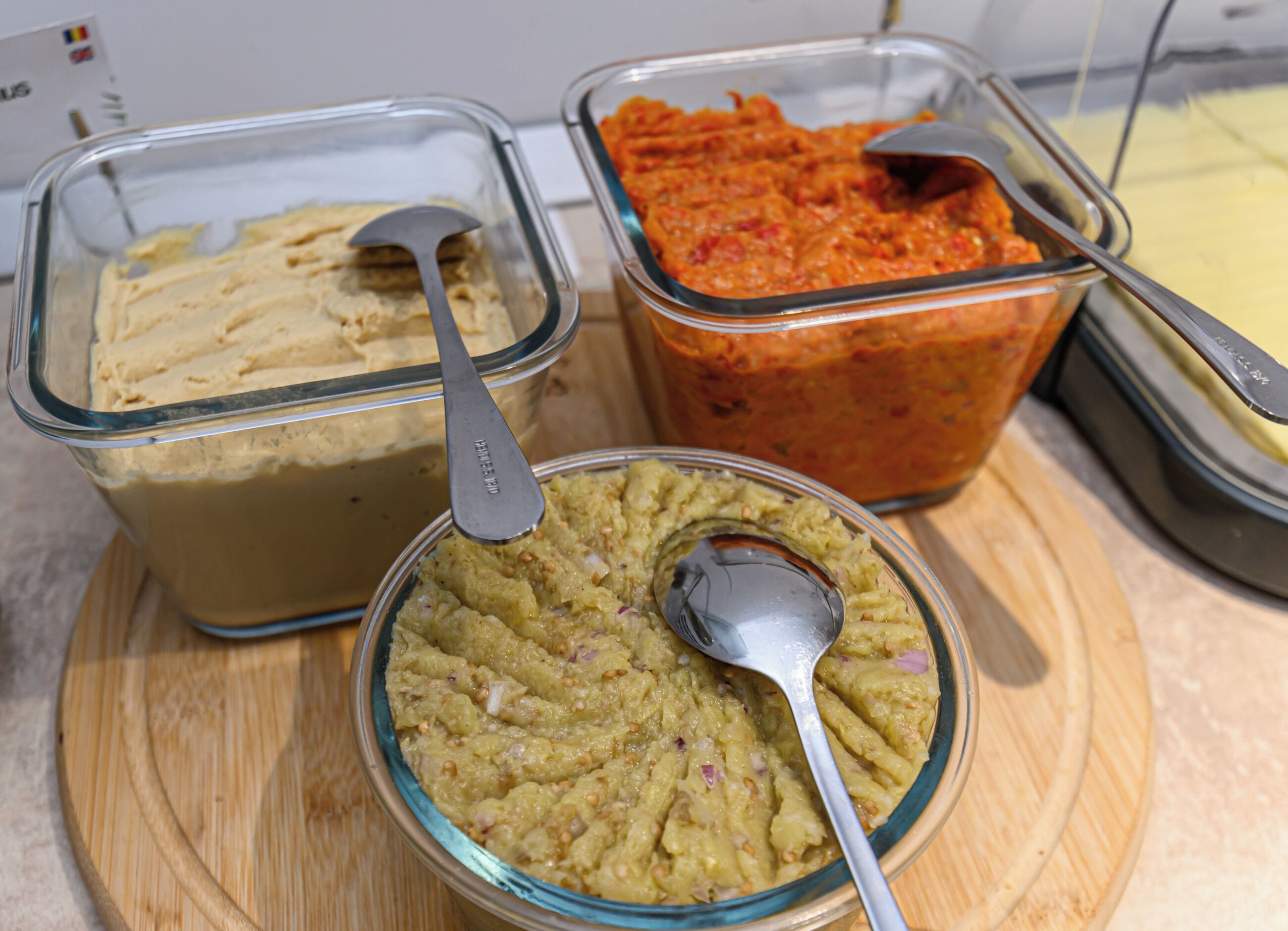Three glass containers with different food items on a wooden board.