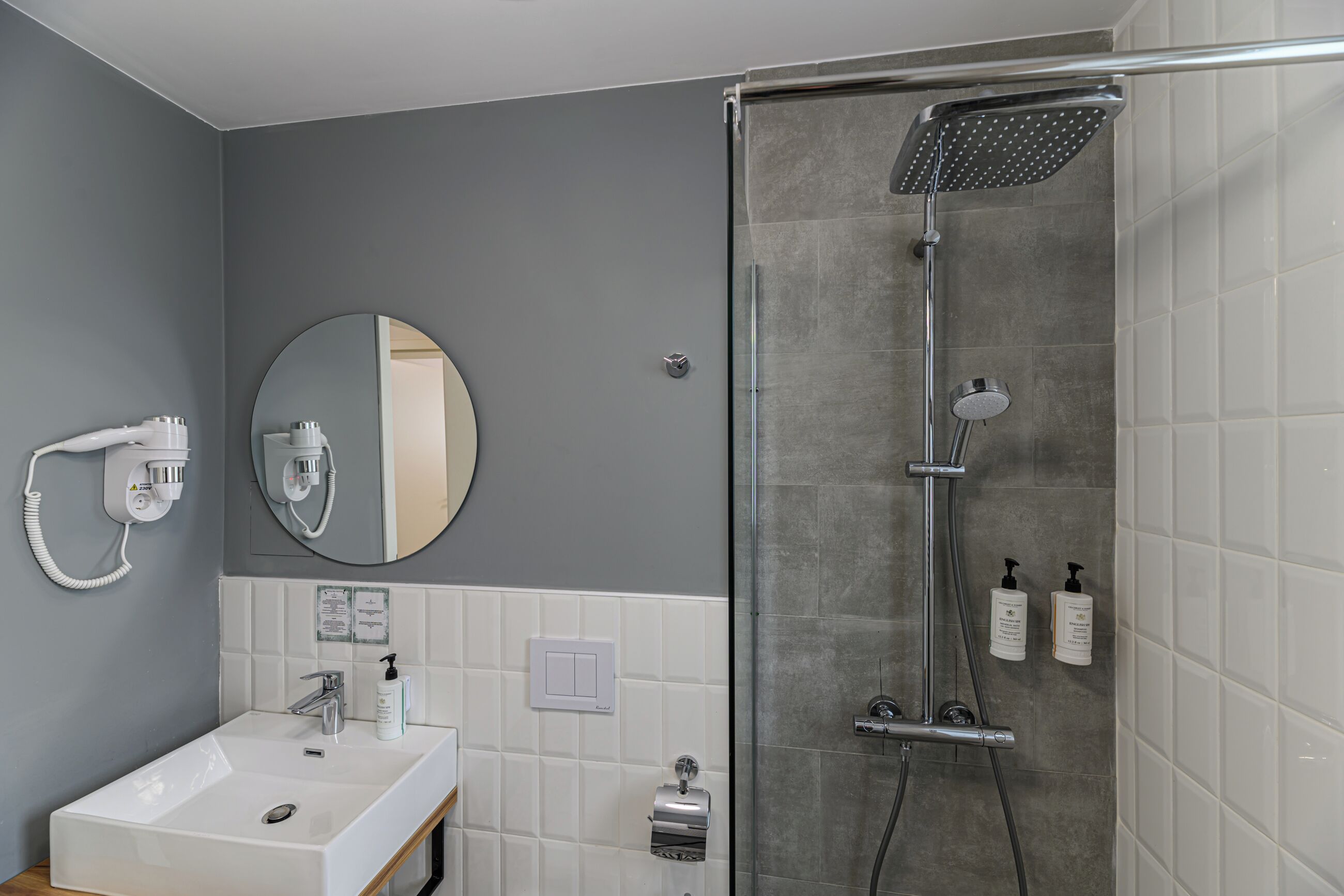 Un baño moderno con ducha, lavabo y espejo.