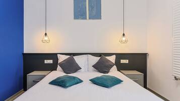 A neatly made bed with two pillows, a headboard, bedside tables, and wall art above.