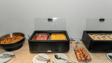 Montaje de buffet con diversos alimentos, como tocino, huevos revueltos y huevos cocidos.