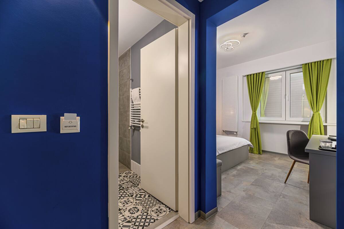 Een moderne hotelkamer met een douche, een bed, een bureau en een raam met gordijnen.