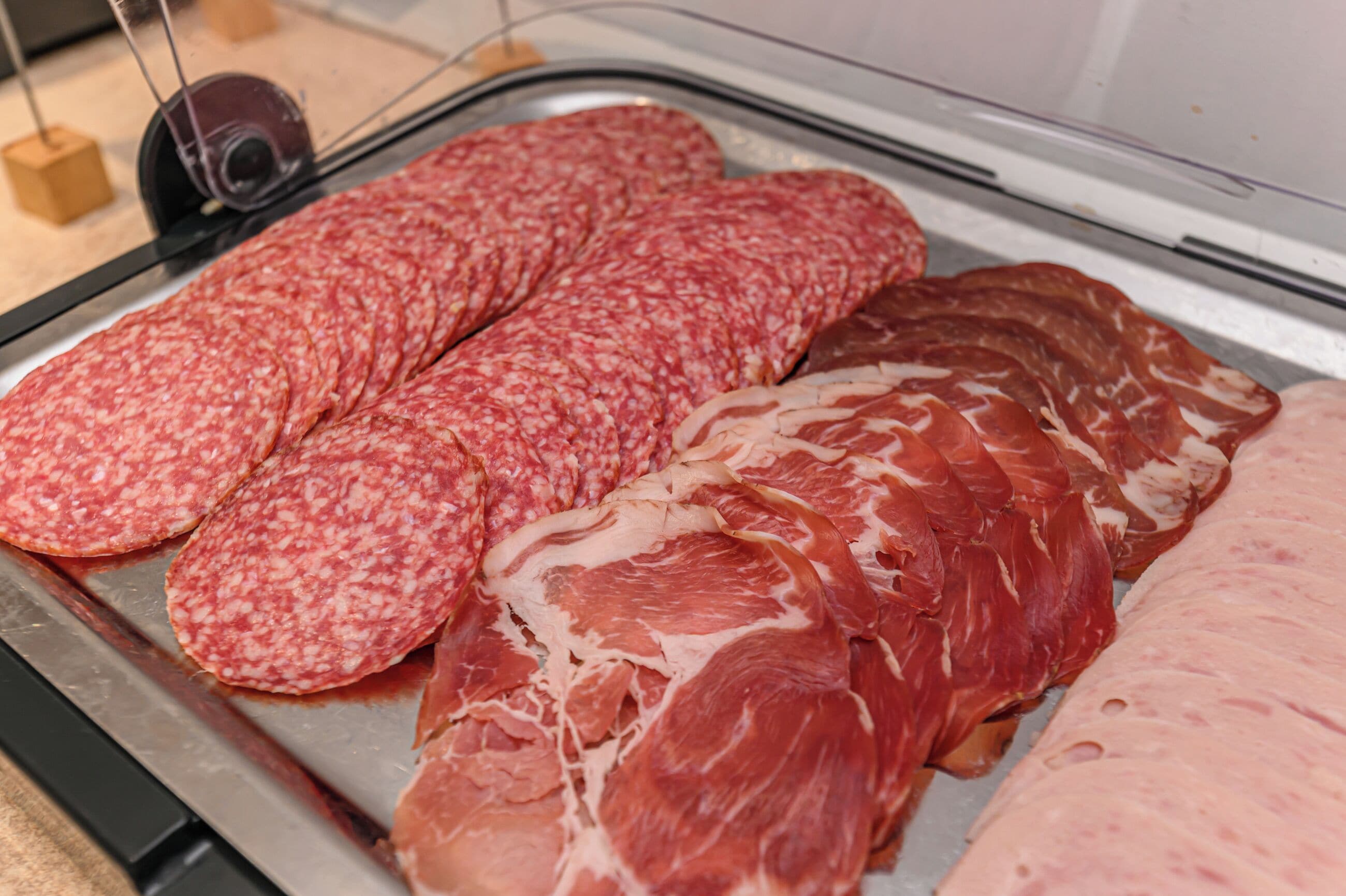 Una bandeja de metal exhibe varios tipos de embutidos curados, incluyendo salami y prosciutto.