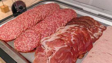 Una bandeja de metal exhibe varios tipos de embutidos curados, incluyendo salami y prosciutto.