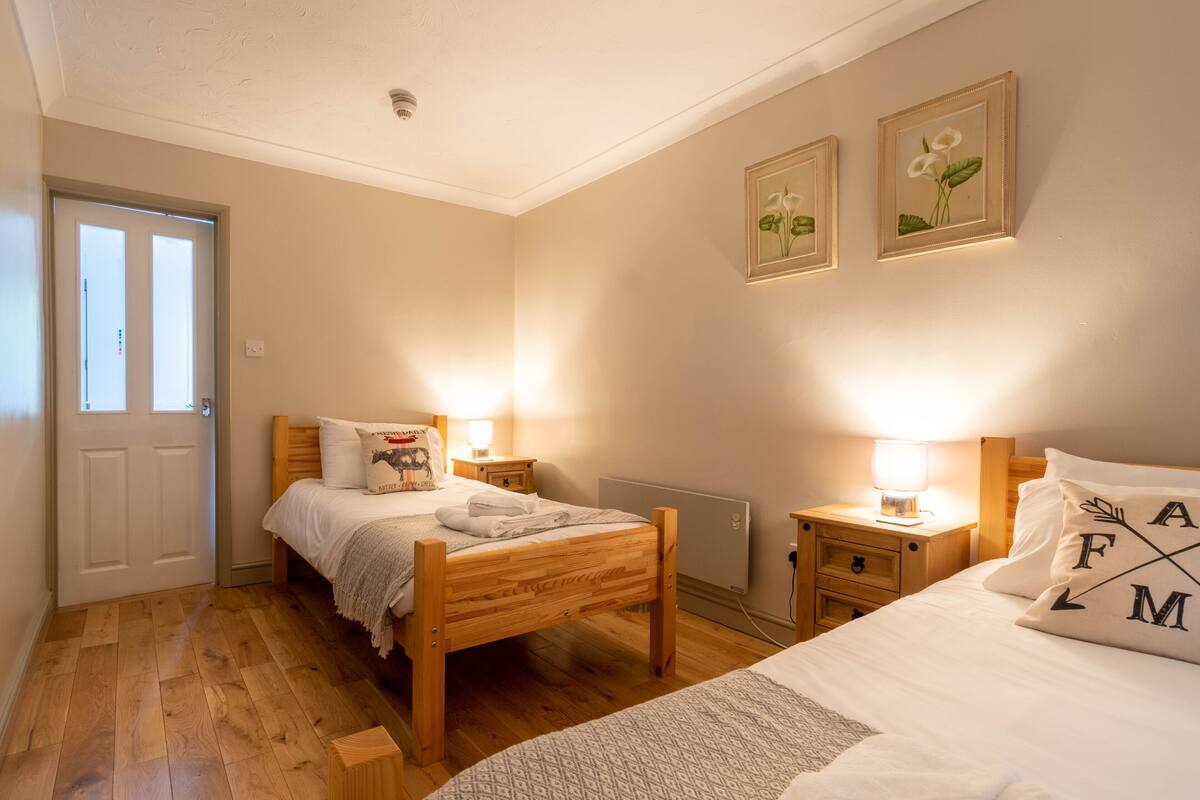 Een slaapkamer met twee houten bedden, een witte deur en een radiator.