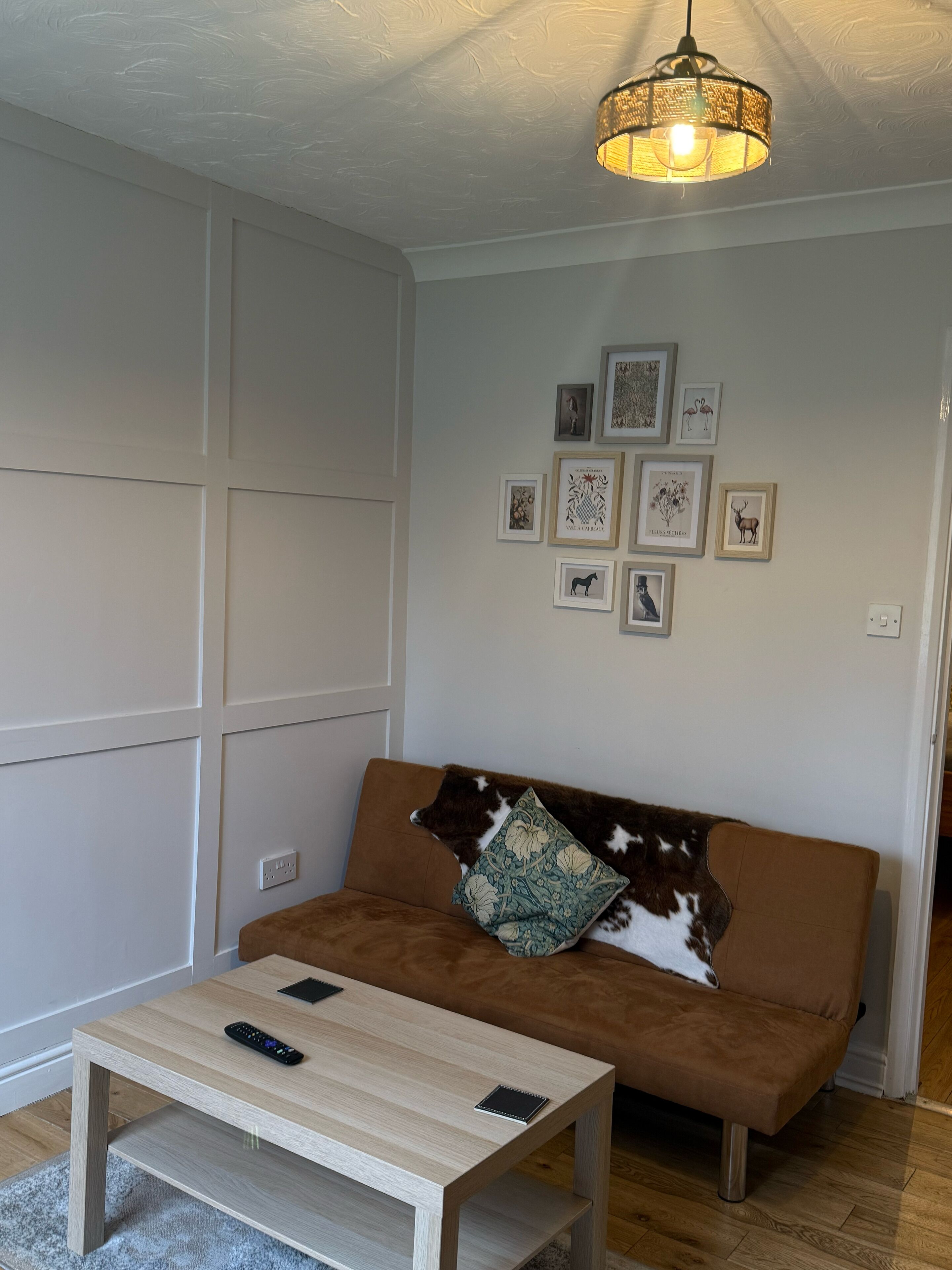 A living room with a brown sofa, a coffee table, and a wall with framed pictures.