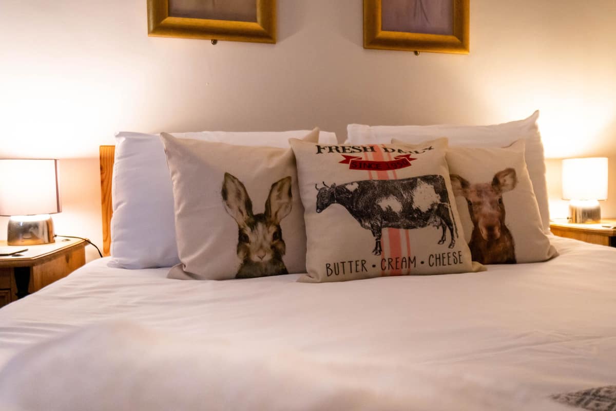 Een bed met witte beddengoed en drie decoratieve kussens met dierenprints.