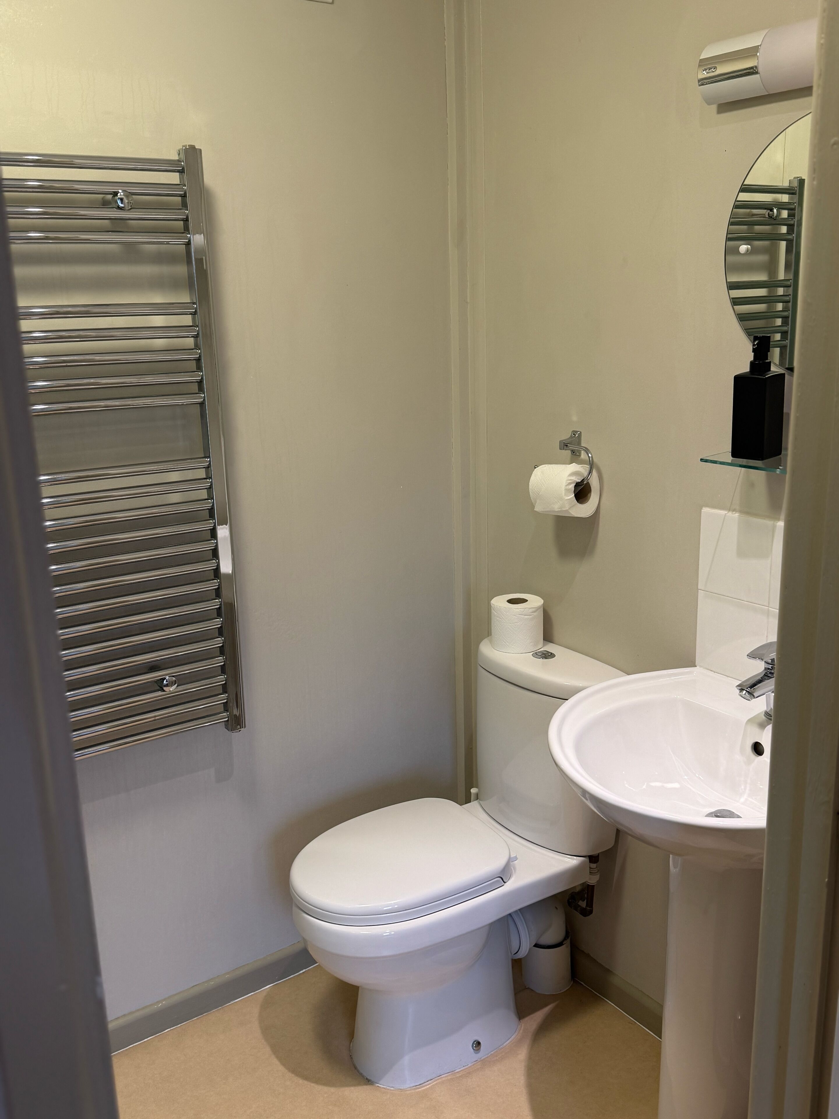 A small, clean bathroom with a toilet, sink, and towel rack.