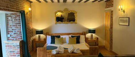 Una habitación acogedora con una cama de madera, dos mesitas de noche, un espejo y una pared de ladrillo.
