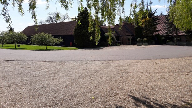 A building with a gravel driveway and a fenced parking area. - The Farmhouse at Fincham (King's Lynn)