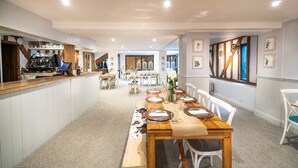 A spacious dining area with a long wooden table set for a meal, surrounded by white chairs. - The Farmhouse at Fincham (King's Lynn)
