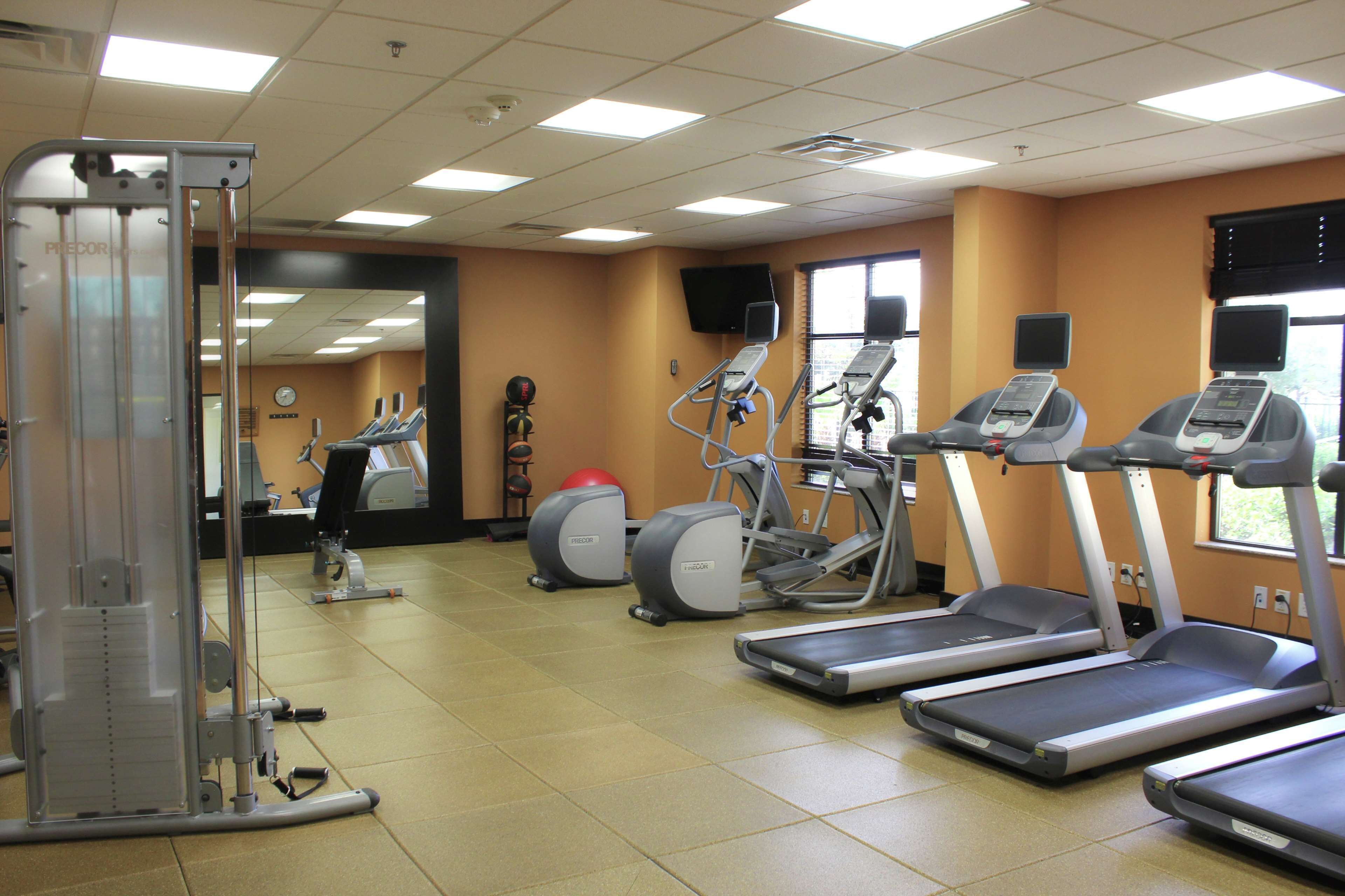 Un gimnasio con cintas de correr, elípticas y máquinas de pesas.