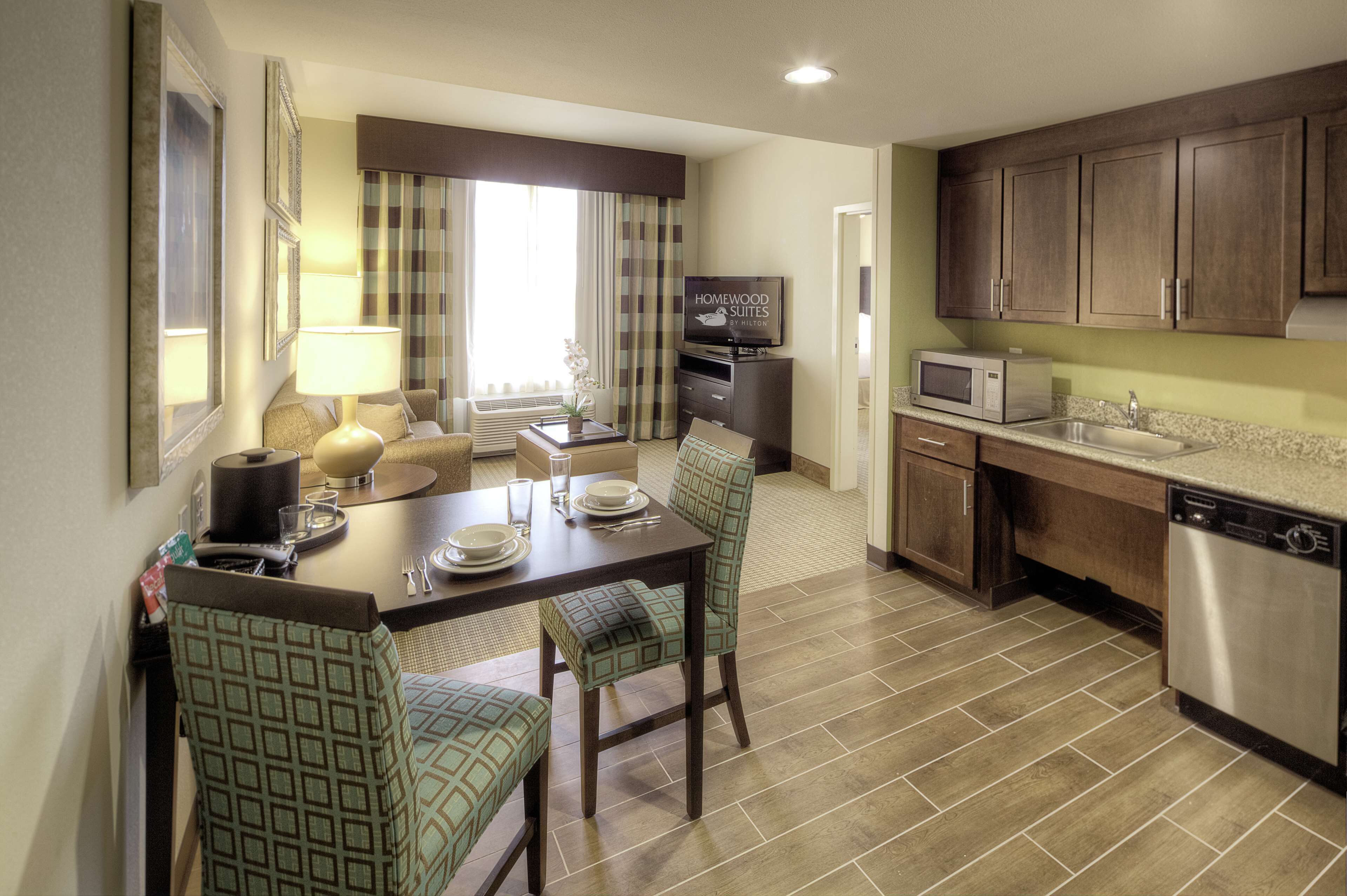 A compact hotel room with a dining area, kitchenette, and a living space.