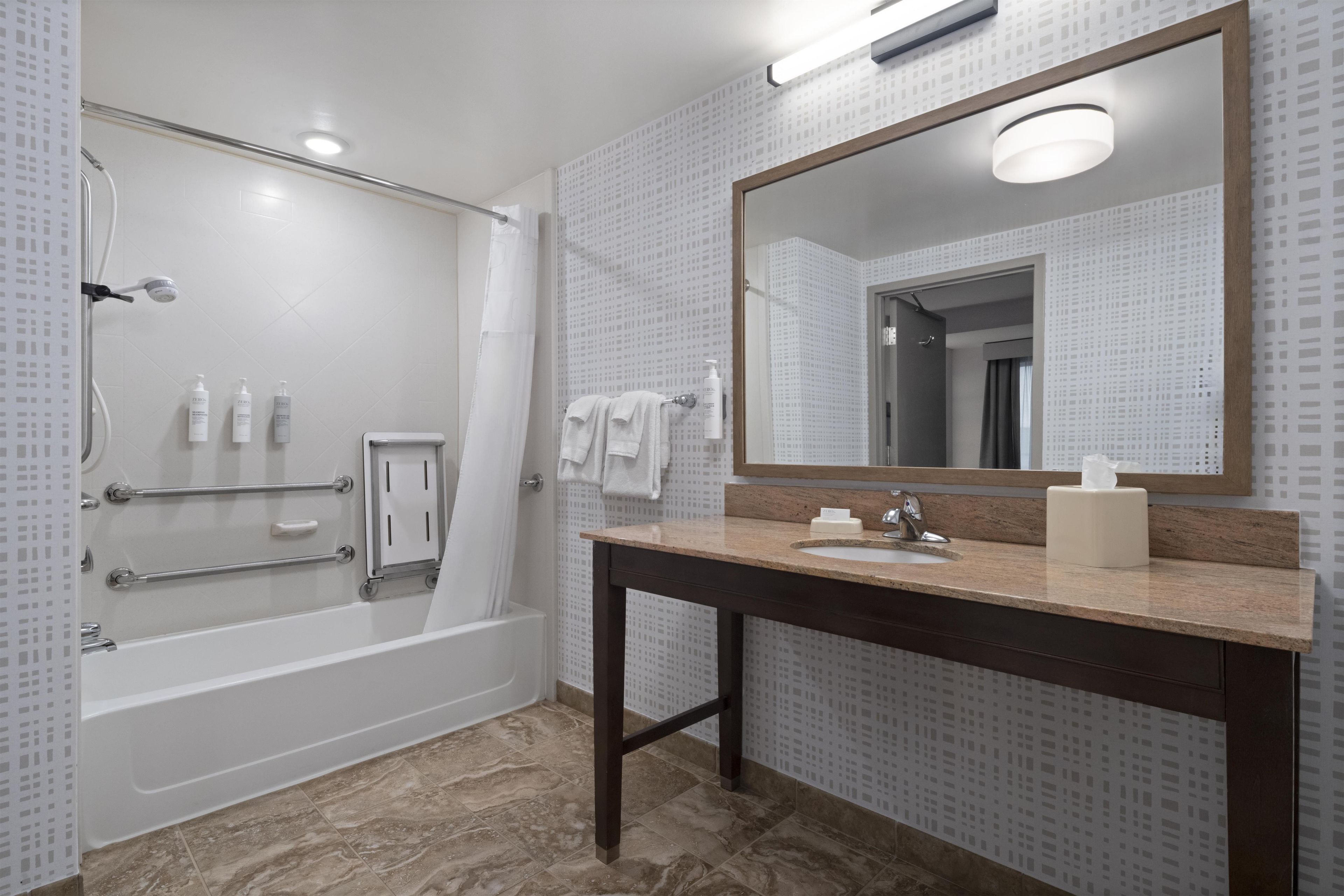 Ein modernes Badezimmer mit Badewanne, Dusche, Waschtisch und einem großen Spiegel.