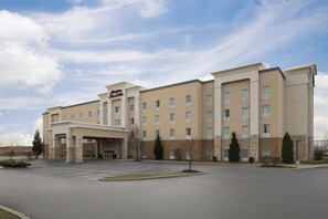 Een Hampton Inn & Suites hotel met een centrale ingang, meerdere verdiepingen en een parkeerplaats.