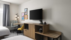 Une chambre d’hôtel comprenant un lit, un bureau avec un téléviseur à écran plat, une chaise et une machine à café.