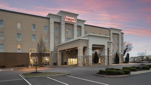 Un hôtel Hampton Inn & Suites doté d’une façade en pierre, de nombreuses fenêtres et d’un parking.