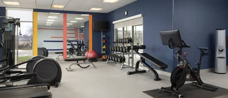 Et fitnesscenter med forskellig træningsudstyr, herunder løbebånd, spinningcykler og vægte.