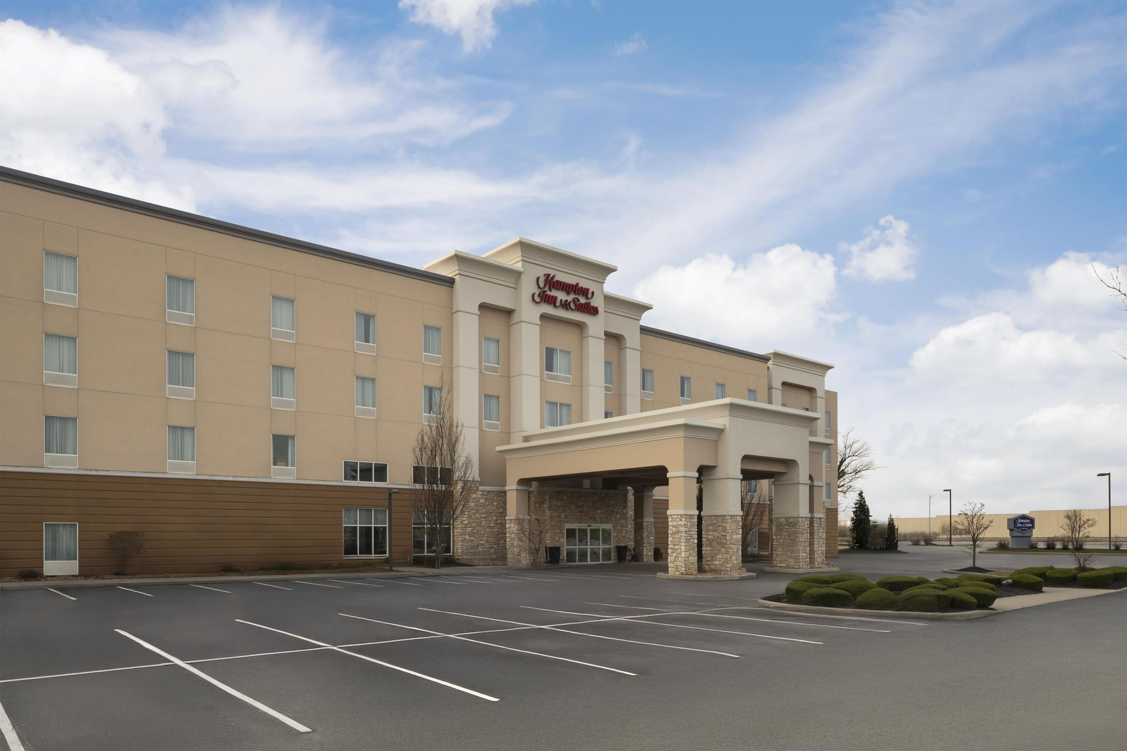 A large, multi-story hotel with a prominent entrance and a parking lot in front.
