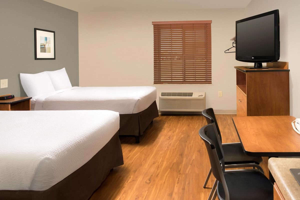 Une chambre d’hôtel avec deux lits, une télévision, un bureau et une chaise.